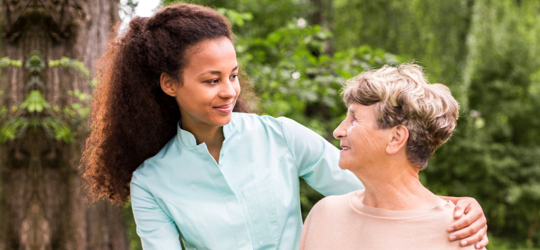 caregiver and senior woman smiling at each other outdoor